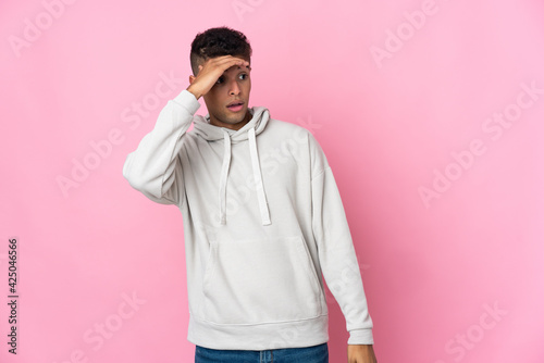 Young Brazilian man isolated on pink background doing surprise gesture while looking to the side © luismolinero