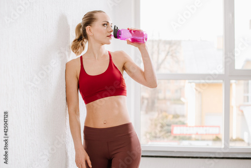 Woman after training posing with water bottle at the gym