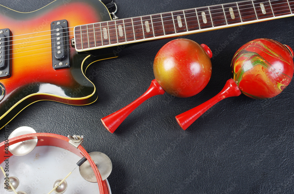 Electric guitar, tambourine and maracas on a dark background. Electric guitar, tambourine and maracas on a dark background.
