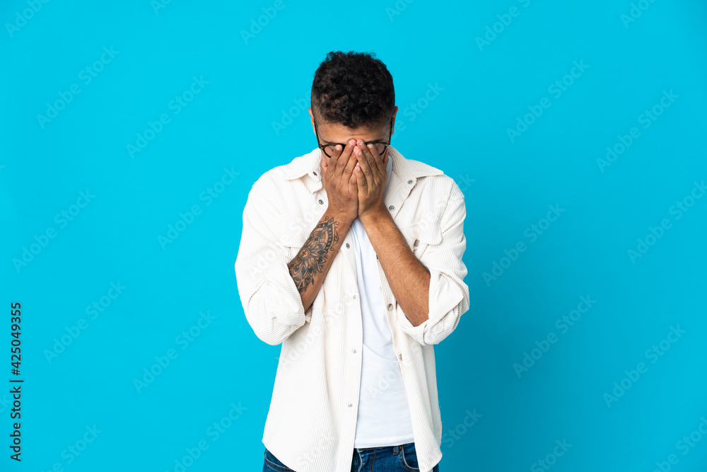 Young Brazilian man isolated on blue background with tired and sick expression