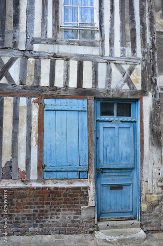 Closeup of a medieval timbered house in the old town of the city Honfleur in the county of Calvados in Normandy, France, built of stone and wood, turquoise door and shutters