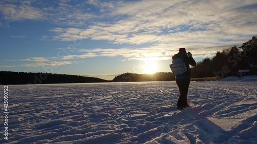 A young woman strolls on the frozen lake at sunset after a sunny day