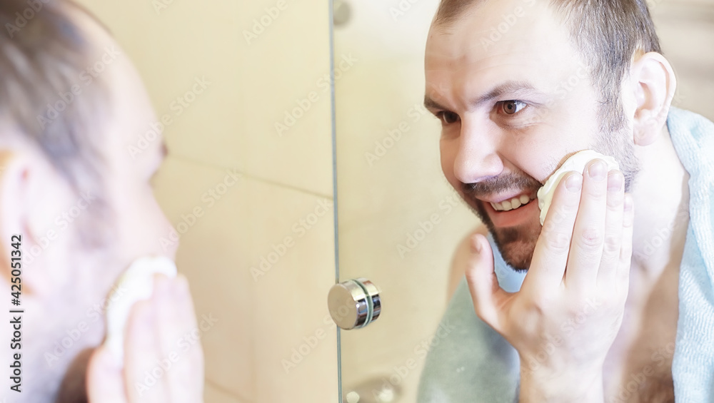 A man shaves in the bathroom in the morning