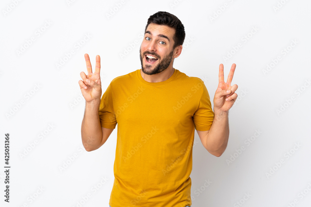 Young handsome man with beard isolated on white background showing victory sign with both hands
