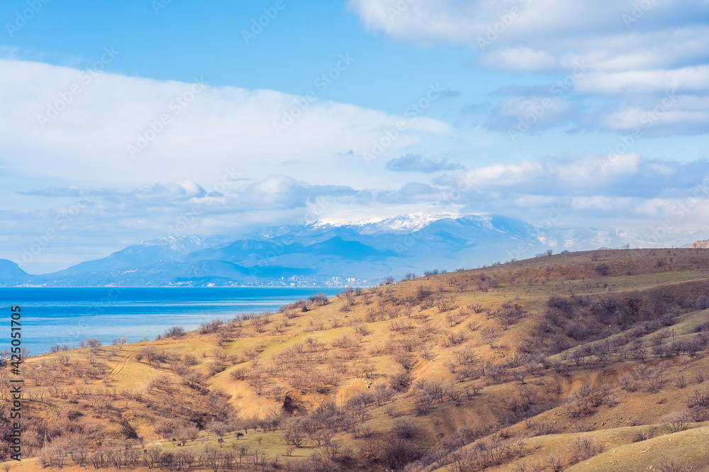 Yellow Mountain in early spring against the background of the sea and a snow-covered mountain range in the morning haze