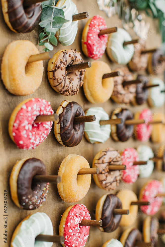 Candy bar with donuts of different colors on a wooden stand