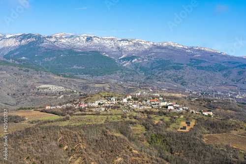 Panoramic view of the snow-capped mountains and the mountain village at their foot in early spring