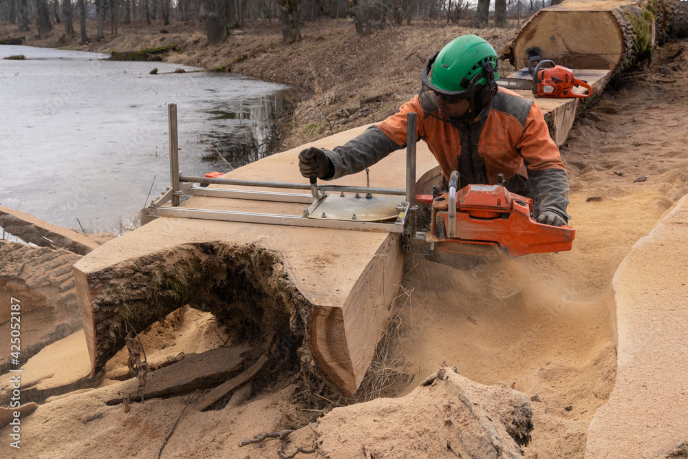 A man cuts boards using a mobile chainsaw mill.