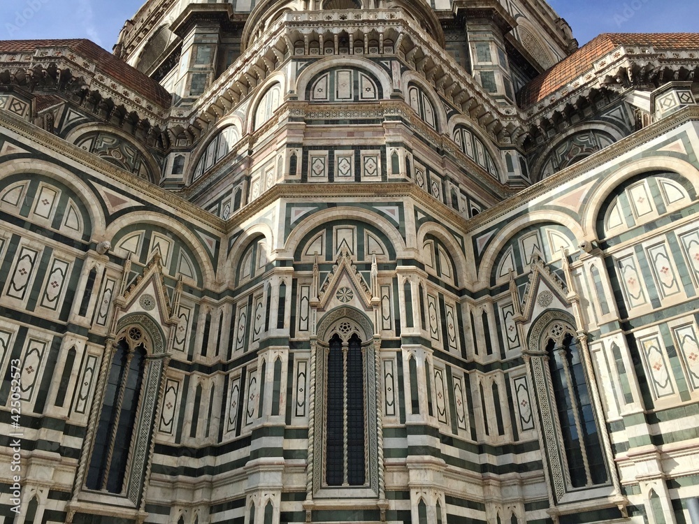 Details of facade of Santa Maria del Fiore in Florence. Italy. White, green and pink marble. Blue sky.