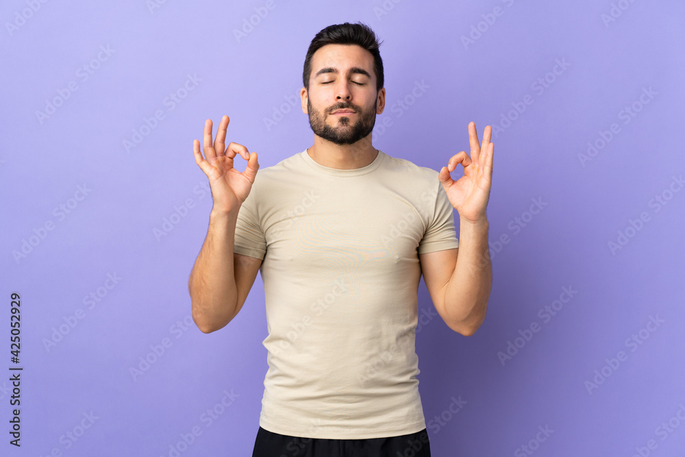 Young handsome man with beard over isolated background in zen pose Young handsome man with beard over isolated background in zen pose