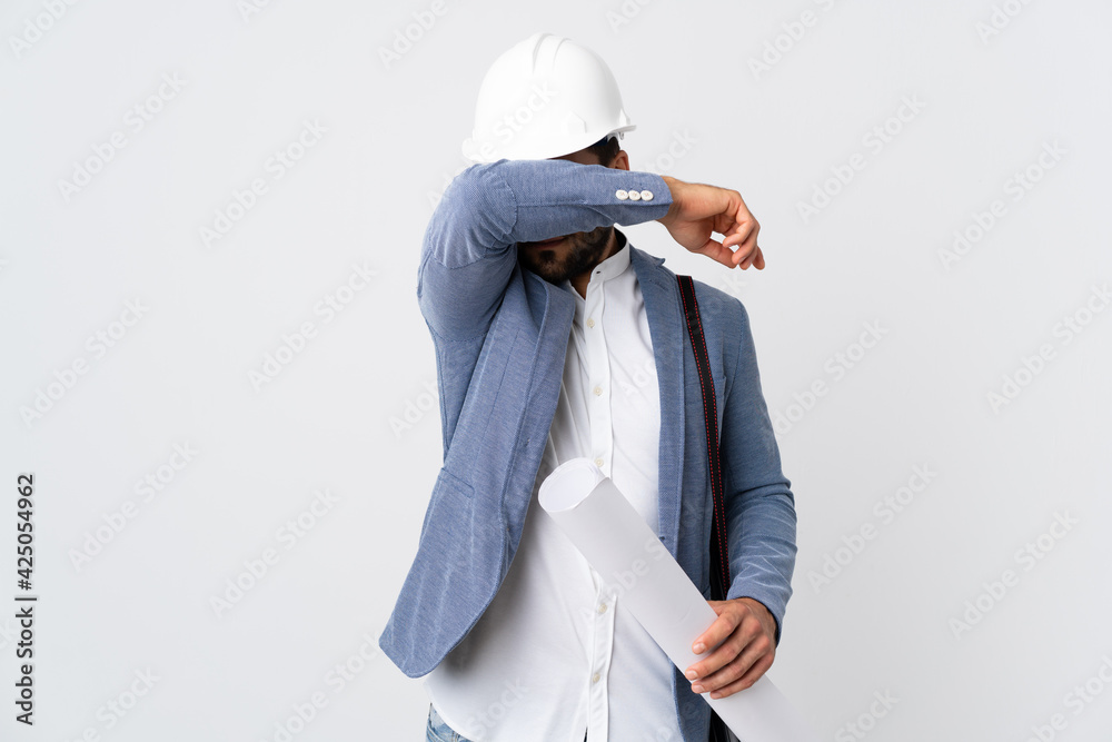 Young architect man with helmet and holding blueprints isolated on white background covering eyes by hands Young architect man with helmet and holding blueprints isolated on white background covering eyes by hands