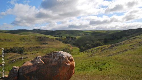 Hills with green grass between Adelaide and the outback in Australia on a cloudy day with blue sky