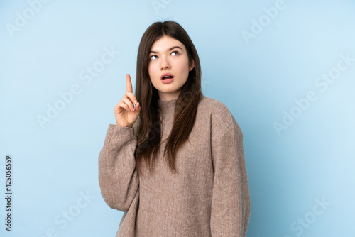 Young Ukrainian teenager girl wearing a sweater over isolated blue background thinking an idea pointing the finger up