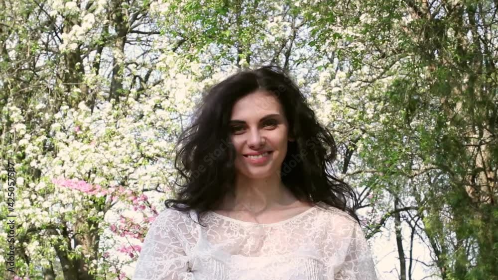 Young girl smiling on the background of spring flowering trees. Young girl smiling on the background of spring flowering trees.