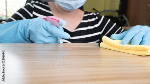 Close up of A young woman housewife in gloves doing chores using cloth with spray fluid detergent on desk at home. Housework concept.