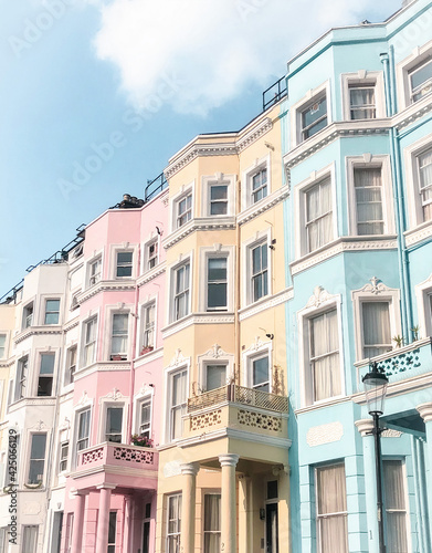 Colourful houses of Notting Hill in London, bring and shiny in the daylight and blue sky above.