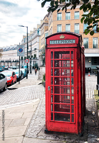 A red telephone booth on the empty street in London.