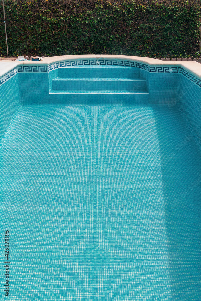 Isolated empty swimming pool with blue tiles