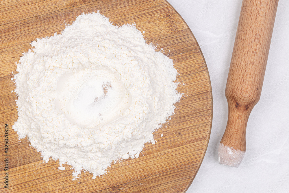 White Flour on the wooden board with rolling pin White Flour on the wooden board with rolling pin