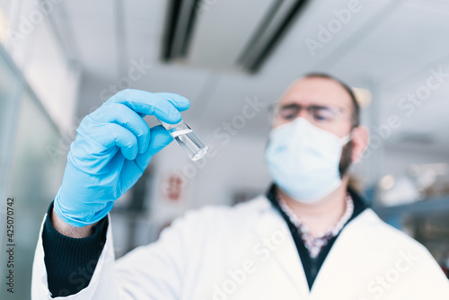 hand with blue gloves holding a glass container with covid-19 vaccine, flu, measles, corona. space for copy space, horizontal picture