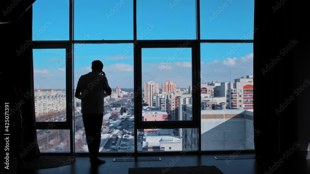 A man speaks on the phone in front of the windows - throws the papers up A man speaks on the phone in front of the windows - throws the papers up