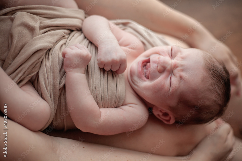 Young mother holding on hands newborn two weeks baby at home in the room. Home portrait of happy fаmily against the window Young mother holding on hands newborn two weeks baby at home in the room. Home portrait of happy fаmily against the window