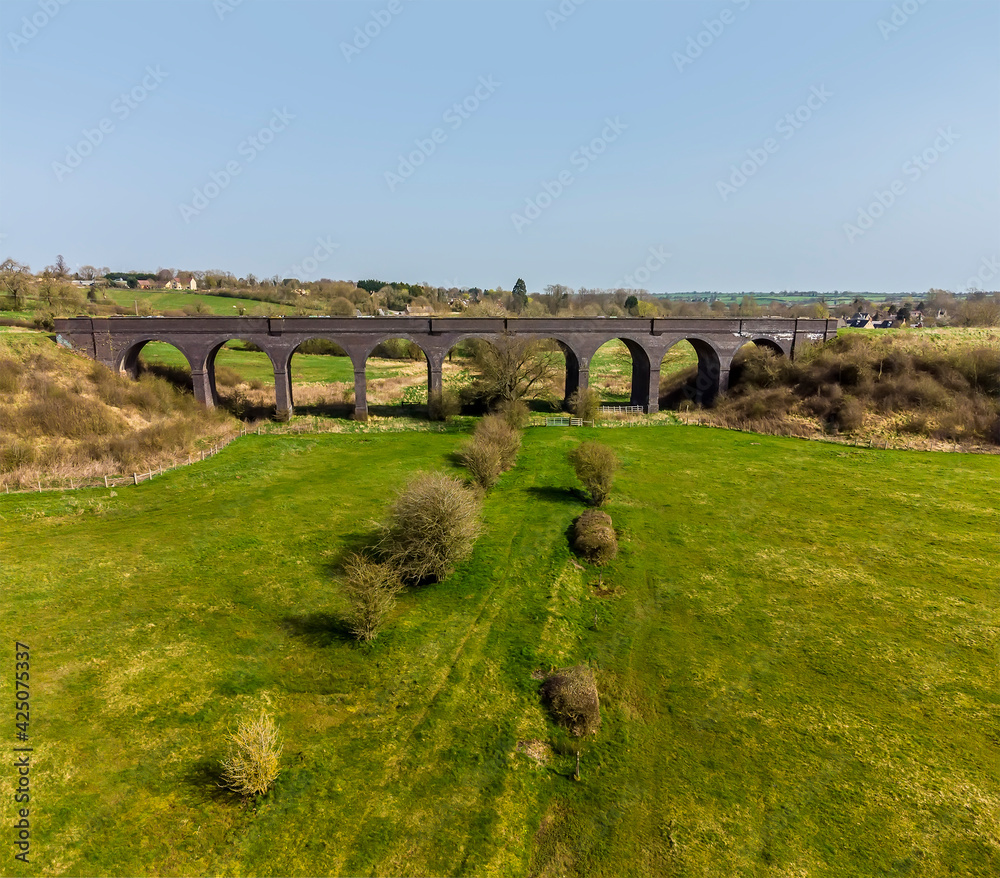 An aerial view across the fields towards the abandoned railway viaduct near to Helmdon, Northamptonshire, UK on a bright Spring day