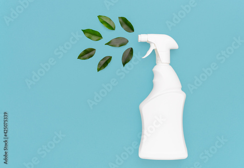 White bottle with a spray bottle and green leaves on a blue background. Organic detergent with natural extract for sustainable spring cleaning, mockup for logo,advertising, organic detergent.top view 
