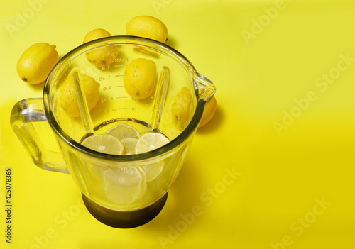 Fruit or Vegetable empty glass Blender with lenon  outside isolated on yellow background. photo