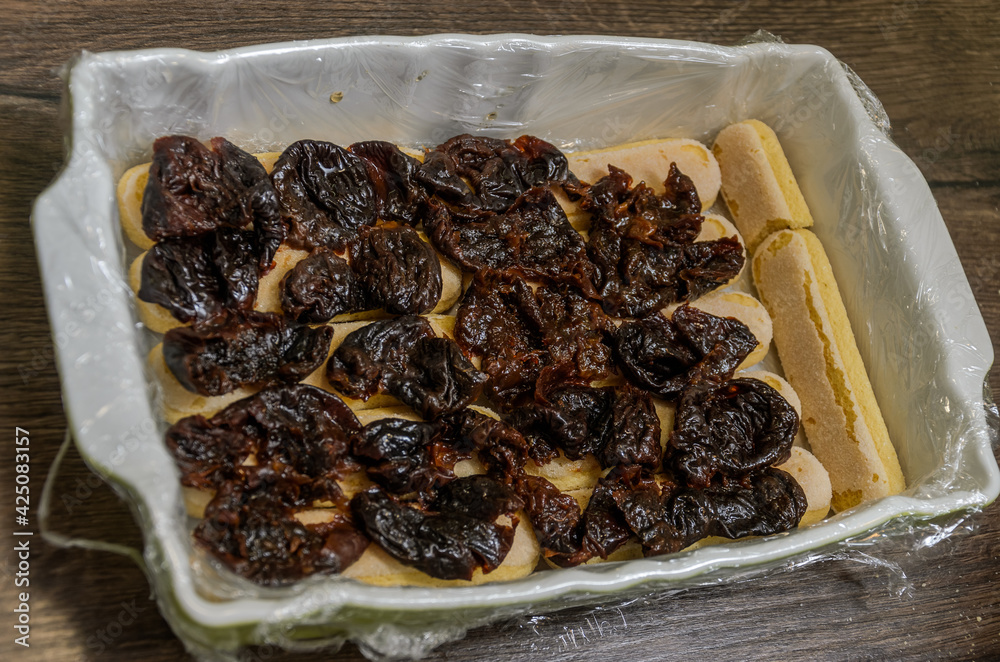 The chef puts the prunes on the cookies in the cake pan
The chef puts the prunes on the cookies in the cake pan