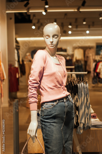 Shop window with mannequins. White girl mannequin on beige background