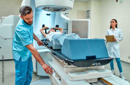 A young woman is undergoing radiation therapy for cancer under the supervision of doctors in a modern cancer hospital. Cancer therapy  advanced medical linear accelerator.