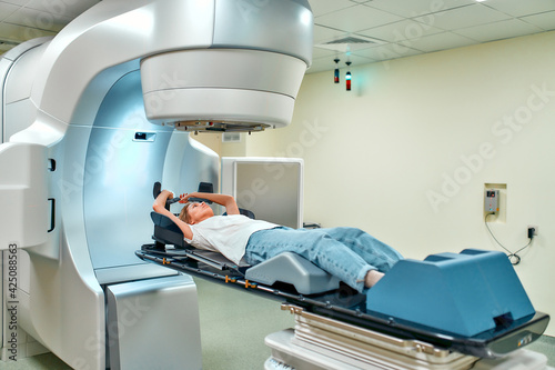 A young woman is undergoing radiation therapy for cancer in a modern cancer hospital. Cancer therapy, advanced medical linear accelerator. photo