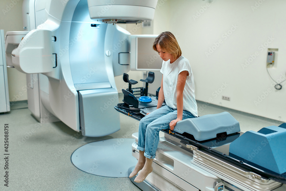 A young woman is undergoing radiation therapy for cancer in a modern cancer hospital. Cancer treatment, modern medical linear accelerator. A young woman is undergoing radiation therapy for cancer in a modern cancer hospital. Cancer treatment, modern medical linear accelerator.