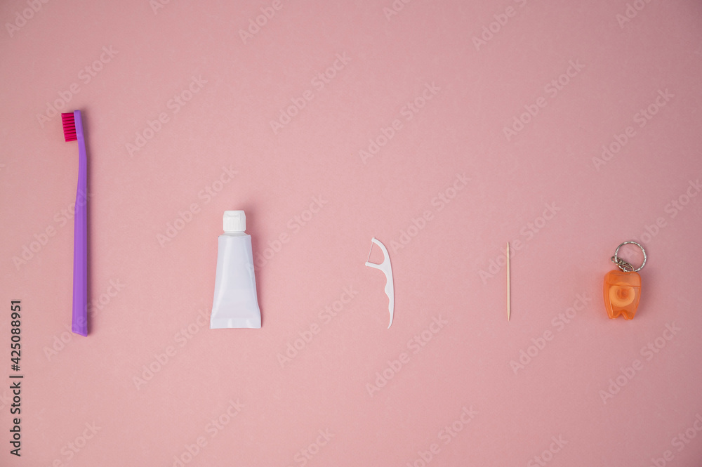 Oral hygiene products on a pink background. Toothbrush toothpaste dental floss and toothpick. Copy space.