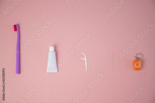 Oral hygiene products on a pink background. Toothbrush toothpaste dental floss and toothpick. Copy space.