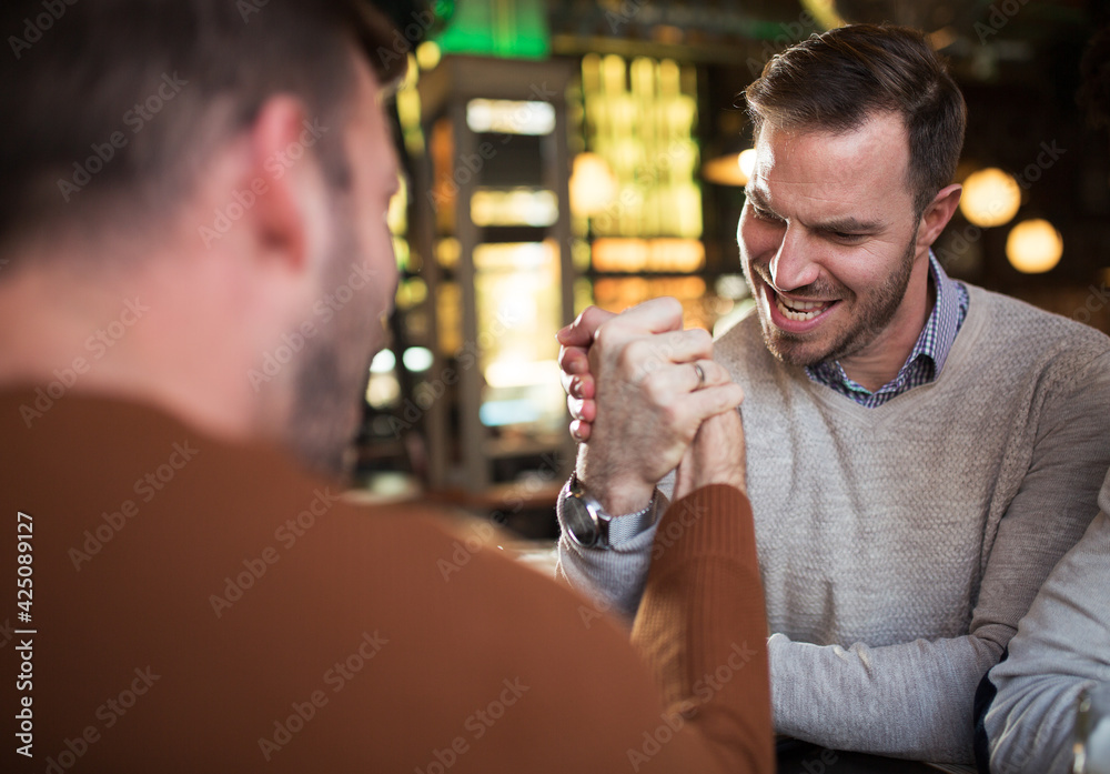 Friends arm wrestling at bar
