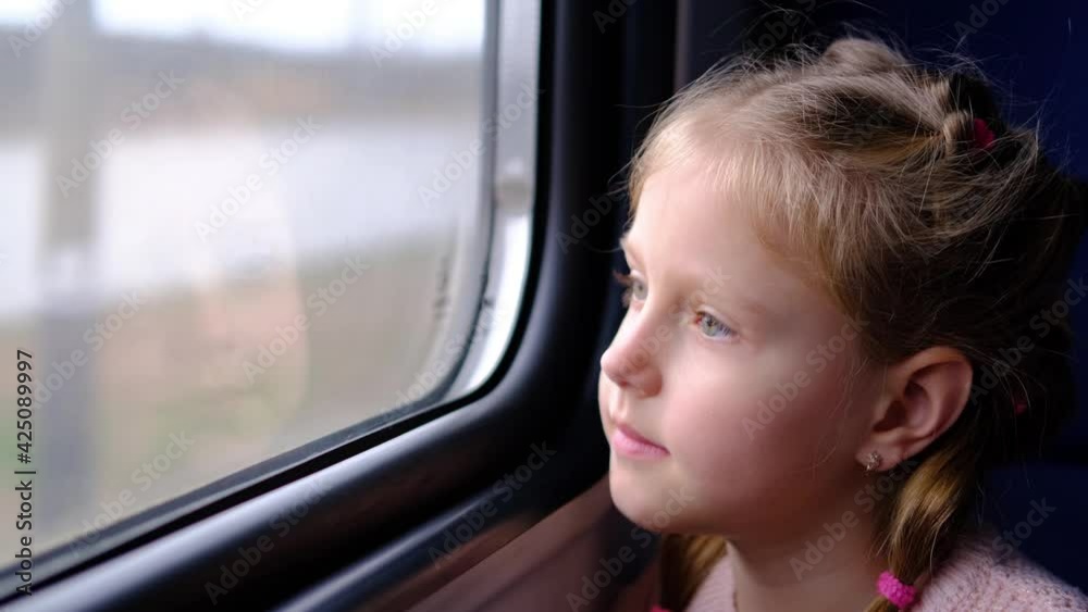 The child is on the train and looks out the window. A little girl travels in a train. The child is on the train and looks out the window. A little girl travels in a train.
