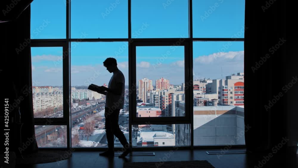 A businessman reads a magazine in an office with panoramic windows A businessman reads a magazine in an office with panoramic windows