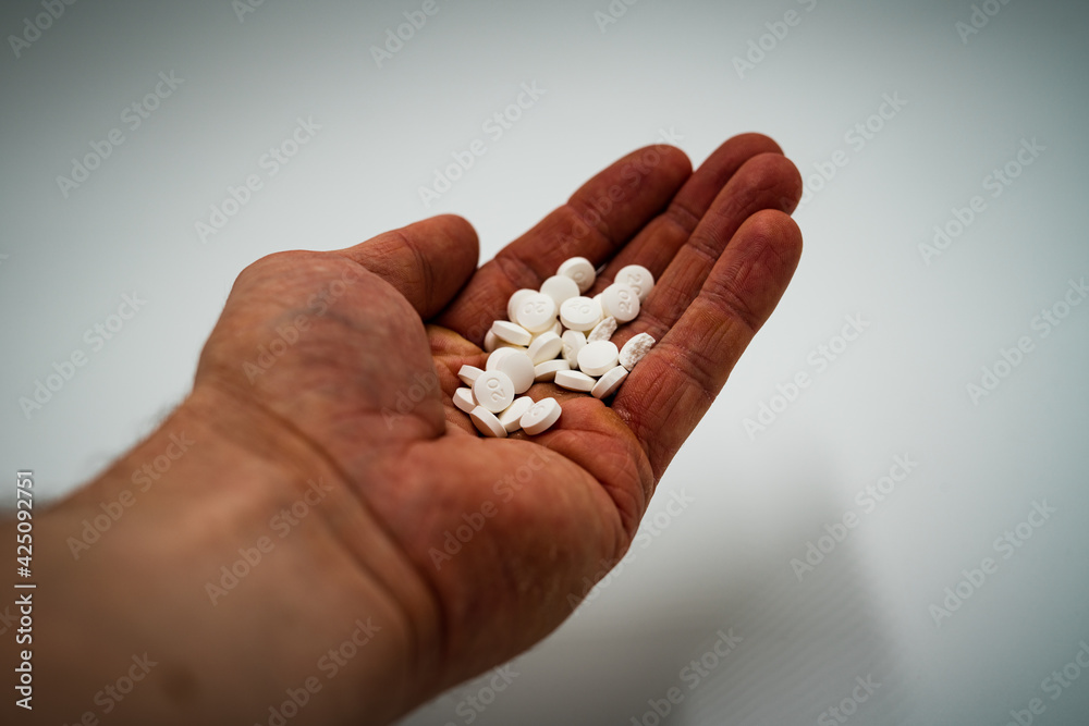 A man holding a bunch of pills in his palm. Danger of overdose. A man holding a bunch of pills in his palm. Danger of overdose.
