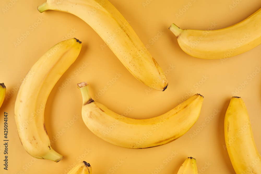 Whole bananas with peel pattern on yellow background, fruits wallpaper