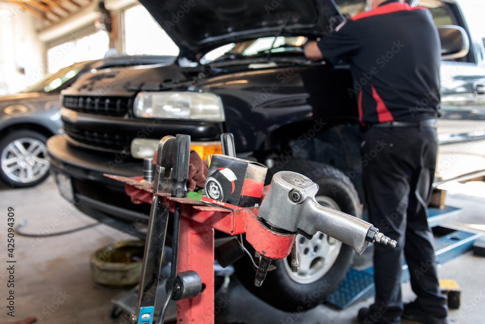 Impact wrench and sockets ready for use by mechanic looking under hood of vehicle during oil change. Impact wrench and sockets ready for use by mechanic looking under hood of vehicle during oil change.