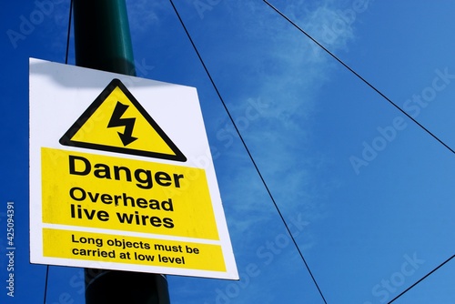 Obraz na plátne UK sign Danger. Overhead Live Wires against a blue cloudy sky.