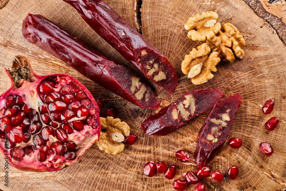 slicing Churchkhela, pomegranate and nuts on a wooden background, top view, serving slicing Churchkhela, pomegranate and nuts on a wooden background, top view, serving