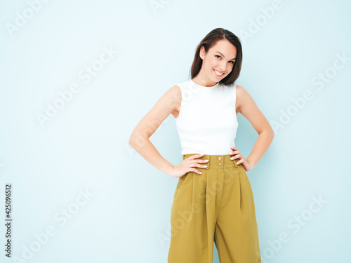 Young beautiful smiling female in trendy summer suit clothes. Sexy carefree woman posing near light blue wall in studio. Positive model having fun indoors. Cheerful and happy © halayalex
