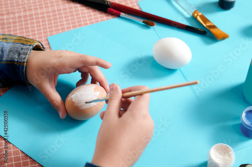 children's hands close up painting easter eggs. Easter table layout with eggs for painting. Preparing for the Easter holiday