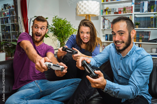 Funny group of friends enjoying video games together. Friends playing games using controller. Concept about lifestyle, technology and people.