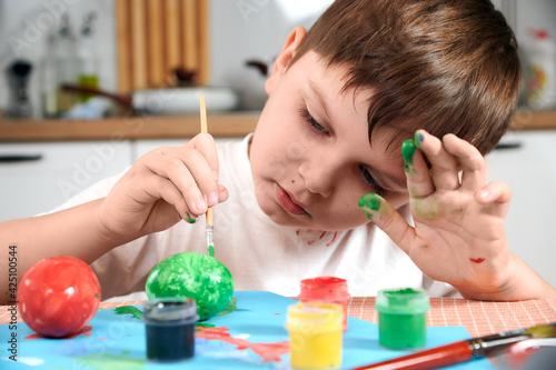 child holds a brush in his hands and paints Easter eggs close up