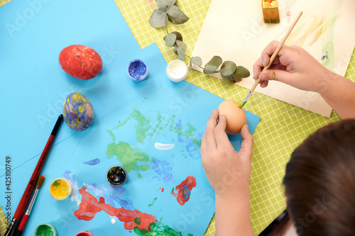 artist's layout. children's hands draw easter eggs at a table with artistic accessories. selective focus 