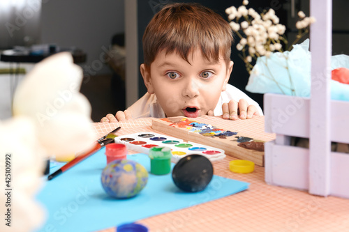 child looks at the Easter egg at the table. surprised child. selective focus 